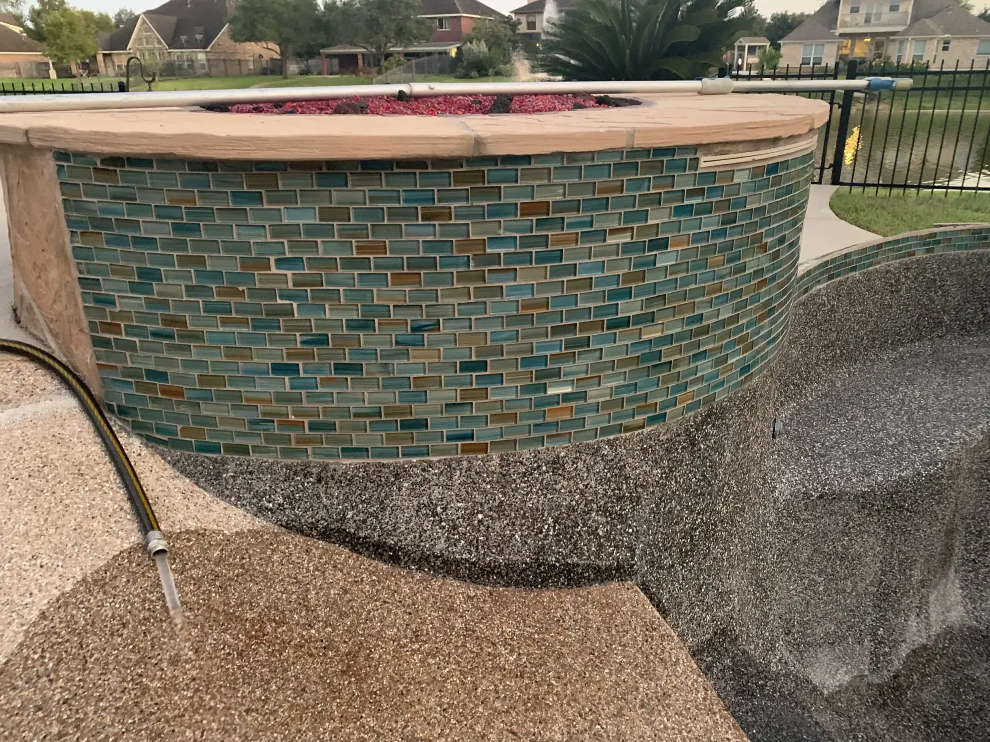 Raised spa finished in iridescent glass tile with a spillover edge