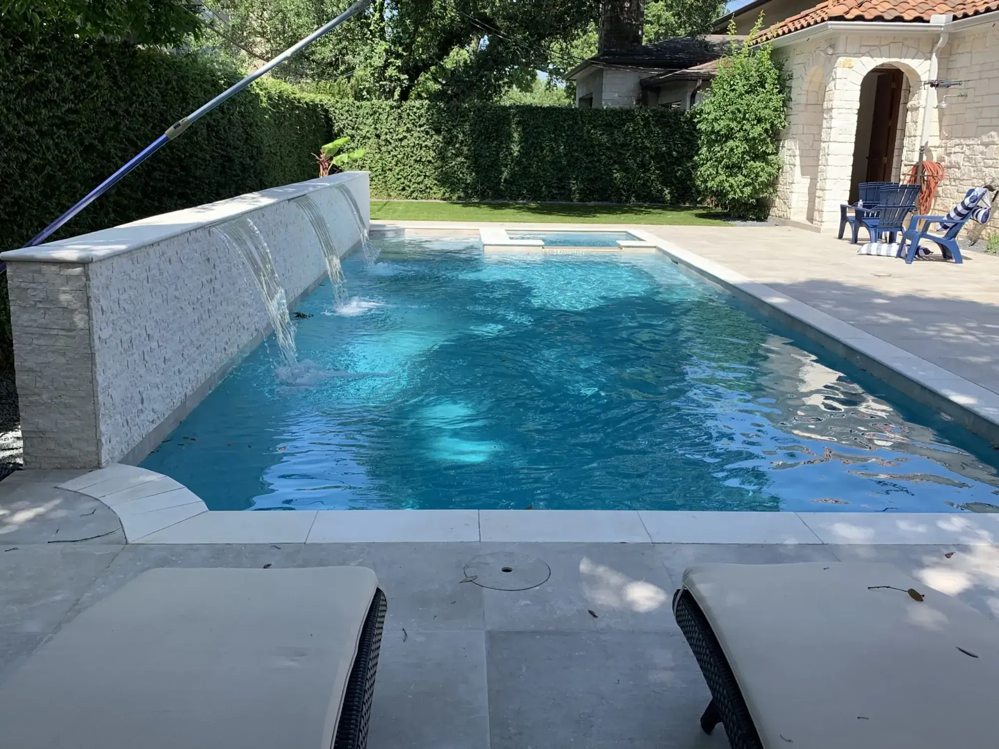 Geometric pool with raised wall and sheer-descent water feature
