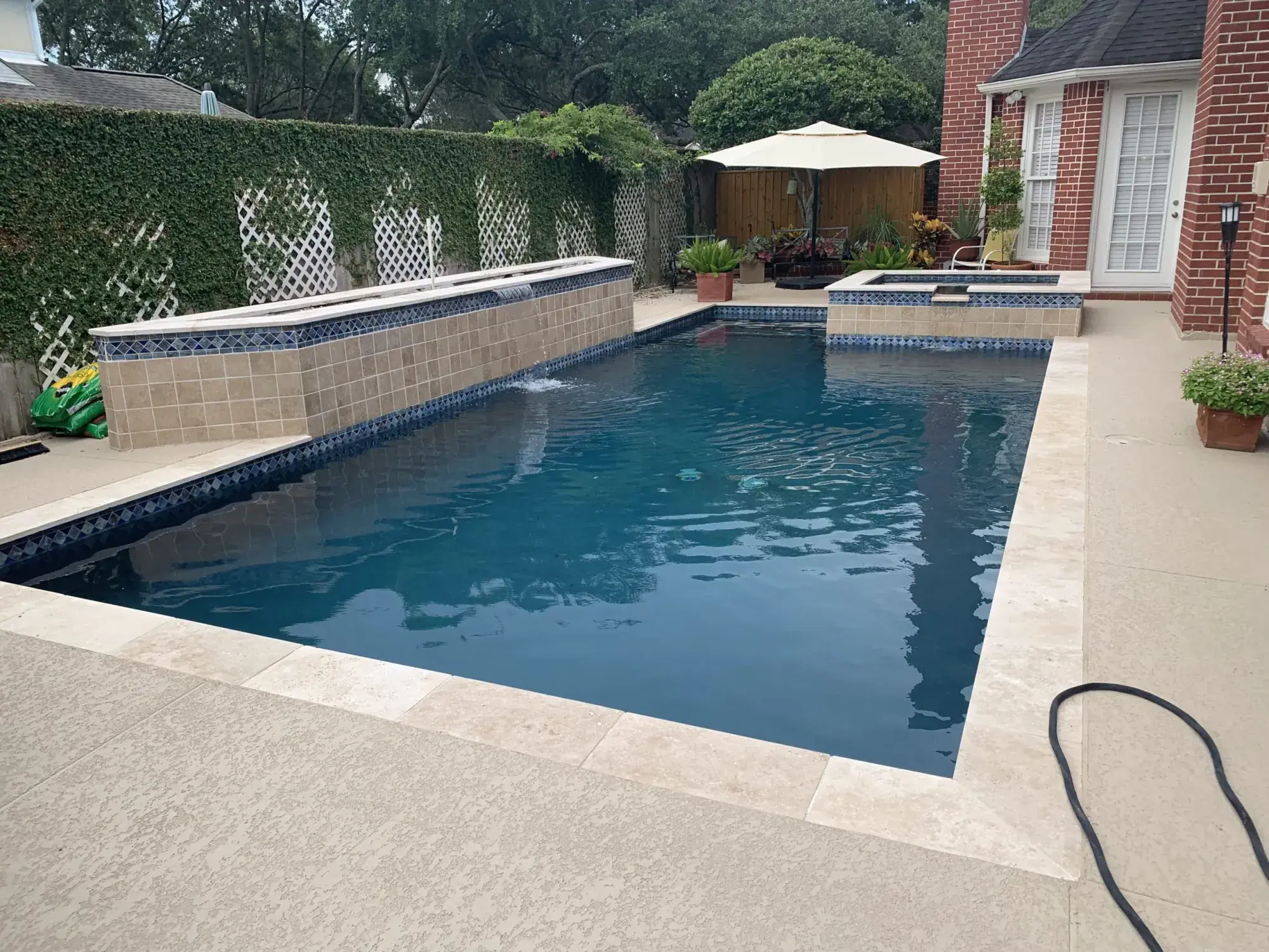 Long geometric pool with dark interior finish and paver surround in Houston