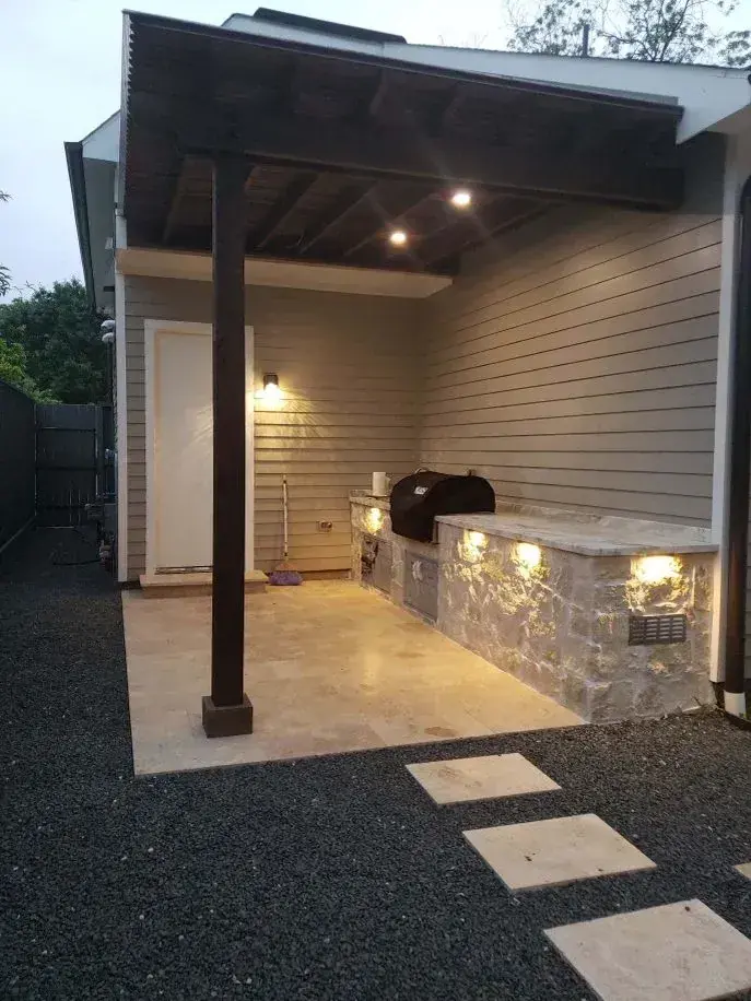 A Venture Pool Company backyard build with a travertine pool deck, pergola, and outdoor kitchen in Houston